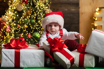 Cute baby face in Santa hat near Christmas tree. Happy Childhood, child 1 year. New year kids.