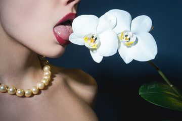 Sexy girl lick orchid flower. Orchids oral tongue. Sensual young woman suck floral orchidea. © Volodymyr