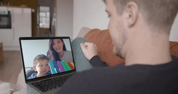 Mother and baby unwrapping birthday present from father on video call using webcam