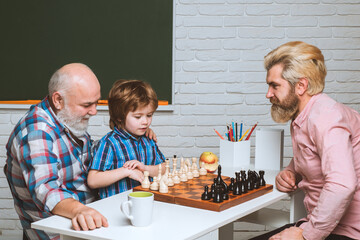 Father grandfather teaching child play chess. Parent and parenthood.