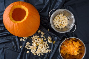 Pumpkin seed harvesting, seeds in a colander and pumpkin guts in a bowl
