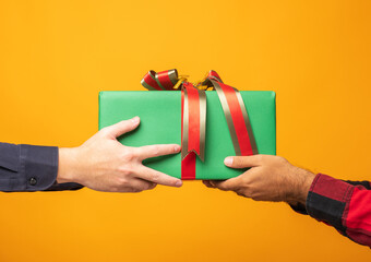 Close up hands giving the present gift box in christmas day on yellow background. Merry christmas and happy new years and sending the gift.
