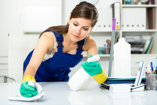 Young female cleaner working productively on task in office. High quality photo