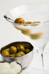 Celebration concept. Frosty Martini cocktail with green olives and onions on marble board. Close up