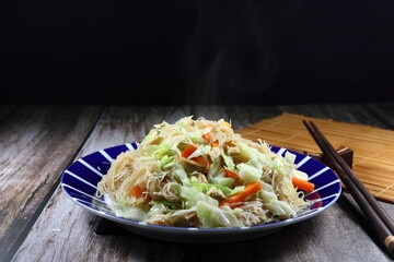Fried and stirred rice noodle with sliced fresh Chinese cabbage, chopped carrot and tofu on the plate. Famous traditional vegetarian menu in Asia restaurant. High fiber and vitamin food. 