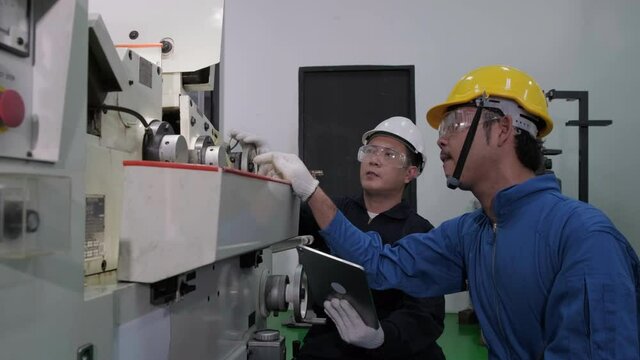 Two Asian male engineers inspect and plan to repair machines in the factory. Engineering and industrial concept.