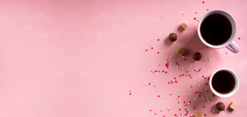 Coffee tea cups, sweets candy chocolate on pink hearts background. Valentines day 14 february minimal concept. Wide banner