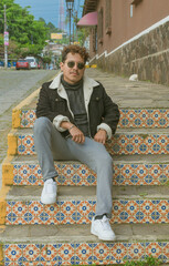 Male model in colorful colonial town. man dressed fashionably in aviator jacket and dark glasses