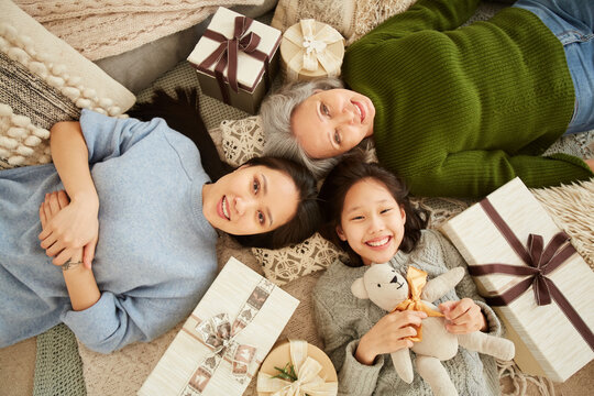 High angle view of Asian family generation lying on the floor among presents and toys and smiling at camera