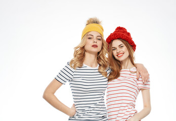 Cute girlfriends fashionable clothes multicolored caps hugs cropped view of communication