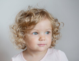 Naklejka premium Curly beautiful European baby girl on light gray background 