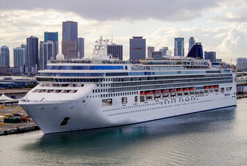 Modern family cruiseship or cruise ship liner during twilight in port of Miami, Florida with city...