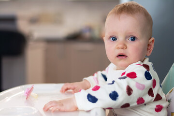 Little baby eating sitting on a child chair. Cute baby eats