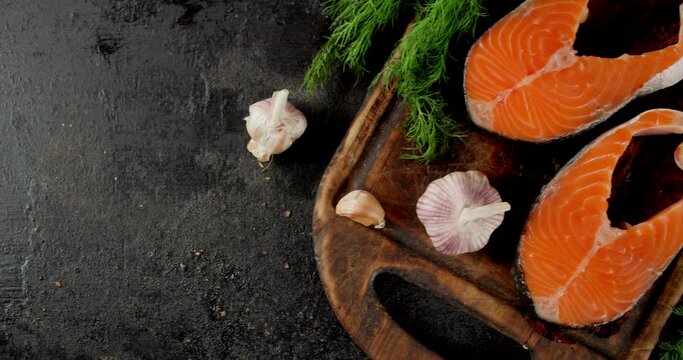 Raw salmon steaks with garlic and dill on the table.