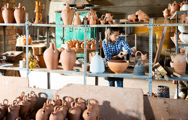 Fototapeta na wymiar Woman chooses pots clay pots in store warehouse. High quality photo