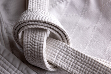 White judo, aikido, or karate belt, tied in a knot on white kimono