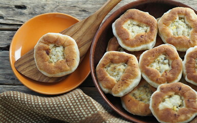 Country style. Homemade cakes, belyashi, in a plate on a wooden background with a wooden kitchen spatula.
