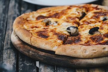 Close up of Italian mushrooms pizza serving on woodedn table. Pizza, a staple of Italian cuisine, has become one of the most recognizable and popular dishes worldwide.
