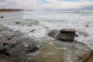 Foaming Waves Crashing onto Rocks in Overcast Conditions