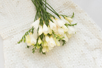 High angle view of white freesia flowers on lace dress - romance concept