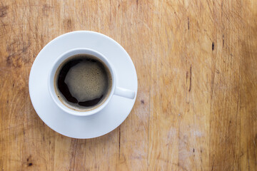 A cup of coffee in a white cup on a wooden background