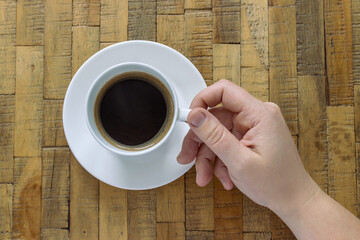 Hand holding white cup of coffee