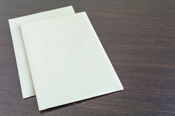 Two blank sheets of paper on a dark texture table. New template of empty sheets of paper on a brown wooden background. Rough surface of pages. Office papers mockup top view closeup.
