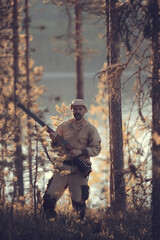Fototapeta premium hunting man / hunter with a gun hunting in the autumn forest, yellow trees landscape in the taiga