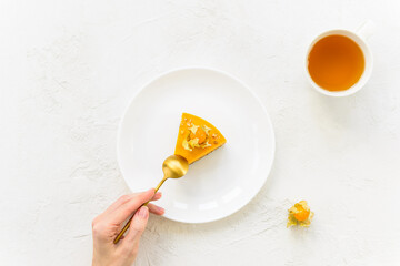 A slice of pumpkin cake with a spoon in hand and a cup of tea. Sugar, lactose, gluten, baking free. Horizontal orientation, top view.
