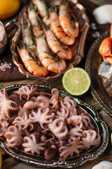 Top close-up view of plates with assorted seafood. Cooked crab, baby octopuses and tiger shrimps served with lime and seashells on rustic wooden background. Seafood concept. Delicious for gourmet.