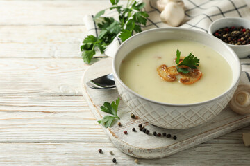 Concept of tasty lunch with bowl of mushroom soup on white wooden background