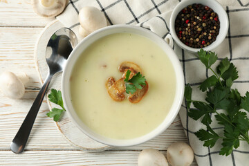 Concept of tasty lunch with bowl of mushroom soup on white wooden background