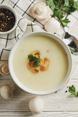 Concept of tasty lunch with bowl of mushroom soup on white wooden background