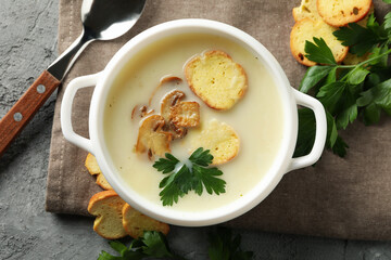 Concept of tasty lunch with bowl of mushroom soup on gray background