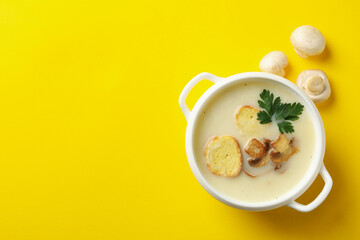 Bowl of tasty mushroom soup on yellow background