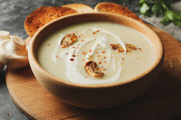 Wooden bowl with tasty mushroom soup, close up
