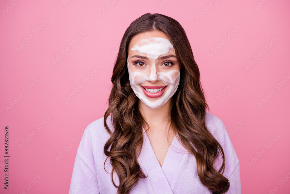 Sticker Photo portrait of attractive smiling young woman with foam mask on face wearing bathrobe isolated on pink color background