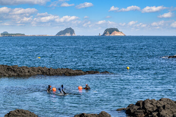 Jeju Island is Korea's leading tourist destination. This is a coastal walkway where you can see two islands. There are haenyeo in the blue sea.