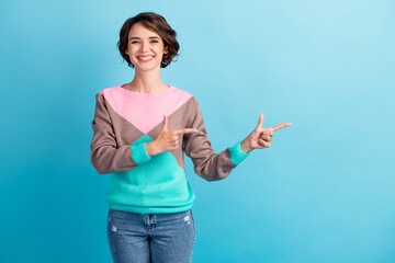 Photo portrait of happy woman pointing two fingers at blank space smiling isolated on pastel light blue colored background