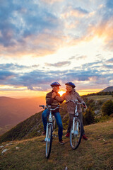 Fototapeta na wymiar elderly couple with bicycles standing at the mountain park kissing