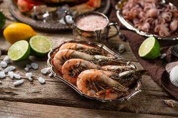 Close-up view of cooked tiger shrimps on plates with crab and baby octopuses background. Seafood concept. Delicious for gourmet.