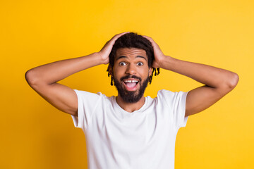 Fototapeta na wymiar Excited dark skin guy open mouth arms touch head listen amazing news wear casual t-shirt isolated yellow color background
