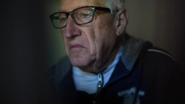 Portrait closeup of a serious elderly handsome white-haired man with glasses reading disturbing news with a puzzled expression on the face. 