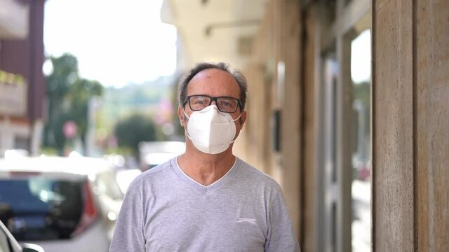 Casual man walking in the city wearing an ffp2 N95 face mask during the Covid-19 Coronavirus pandemic. Looking at camera.