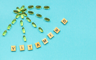 Yellow capsules in the form of the sun with rays and word vitamin D from wooden cubes with letters...