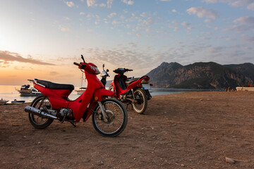Morning on the beach in the village of Cirali, red scooters stand on the beach., morning scooters ride. . Landscapes of the Lycian Trail.