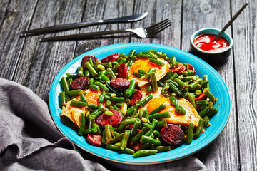 Green beans fried eggs and chorizo on a blue plate