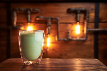 Cup of matcha drink on the wooden table in cafe.