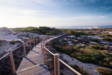 Wooden pedestrian walkway through Sintra-Cascais natural park. Wild sandy landscape, with part of Cresmina Dunes. Beautiful scenery in Portugal.