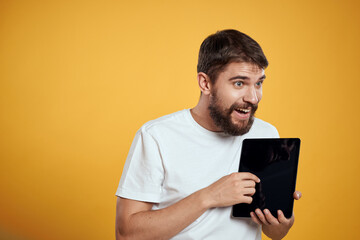 Man with a tablet on a yellow background in a white t-shirt new technologies businessman touch screen touchpad